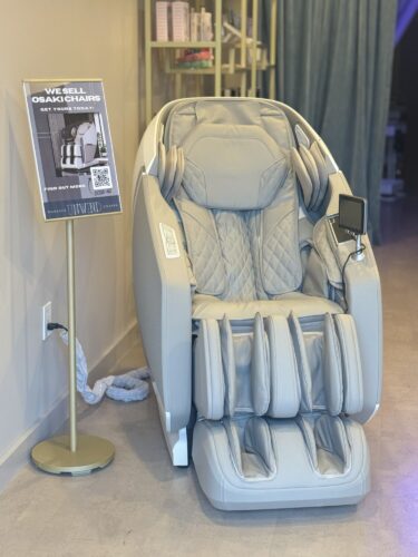 A modern Osaki massage chair with a display screen and headphones.
