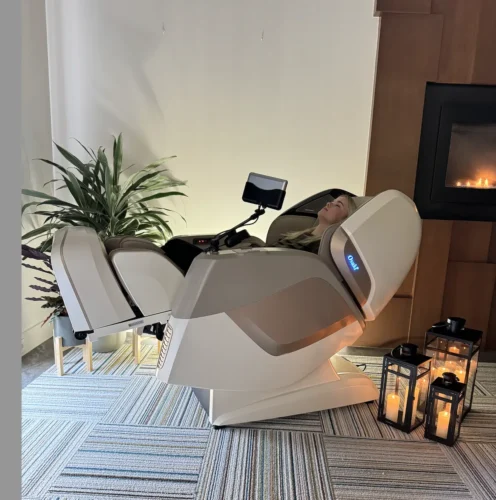 Person relaxing in a modern massage chair with ambient lighting.