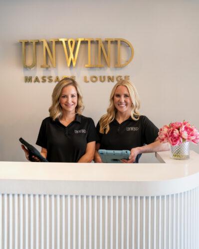 Amanda George and Jessica Smith standing at the front desk of their walk-in massage lounge