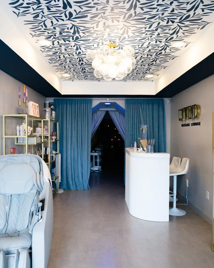 Elegant spa reception with floral ceiling and blue curtains.