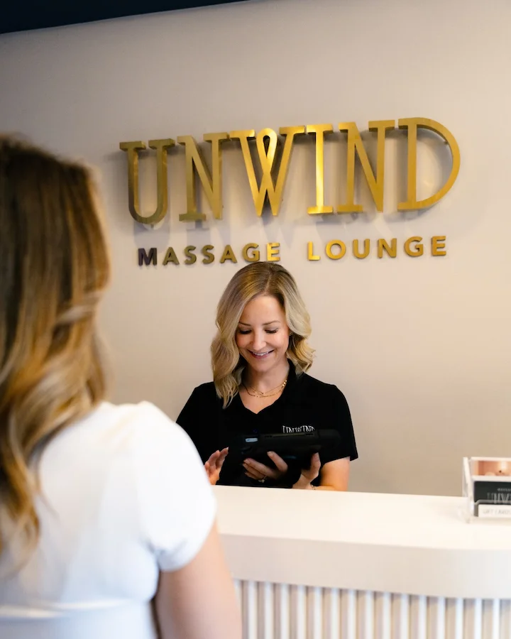 Receptionist assisting a client at Unwind Massage Lounge.