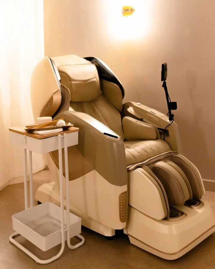 Modern beige massage chair in a cozy room with a small side table.