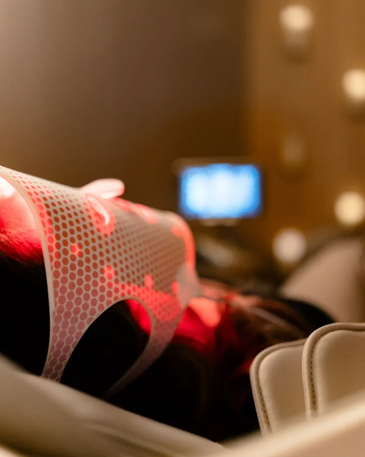 Person wearing a red light therapy mask while relaxing indoors.