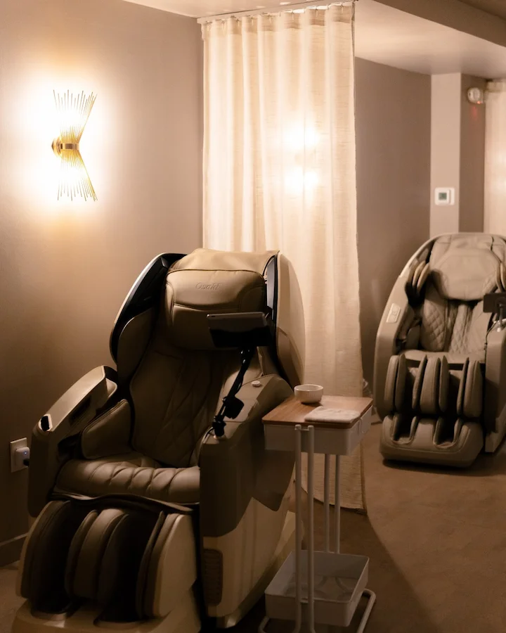 Two modern massage chairs in a softly lit relaxation room.