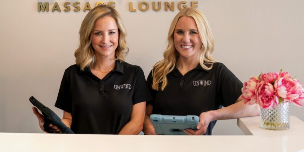 Amanda George and Jessica Smith standing at the front desk of their walk-in massage lounge